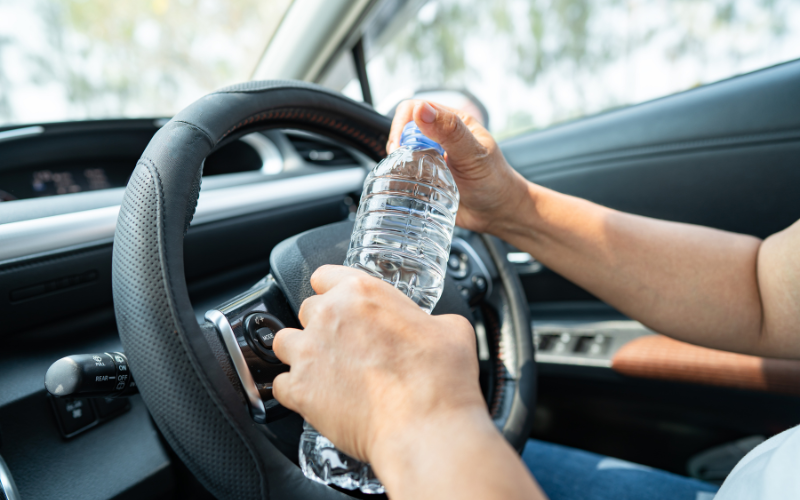 Woman holding bottle of water inside car