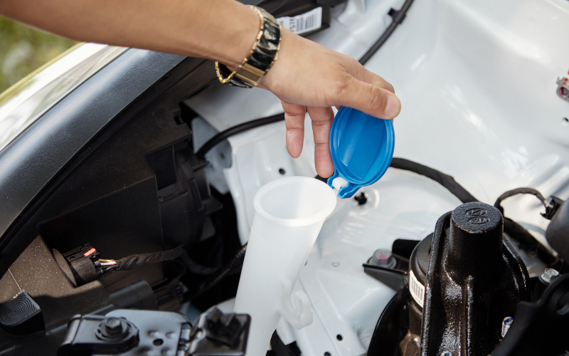 Close-up of man checking windscreen washer reservoir