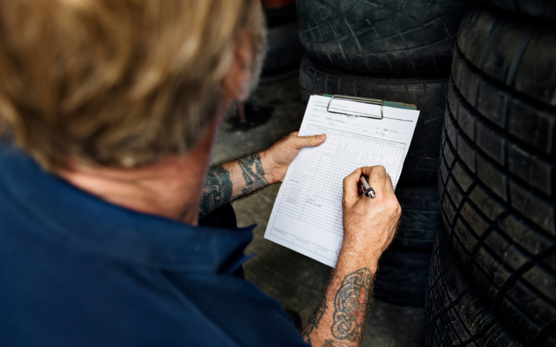 Technician with a checklist next to a stack of tyres