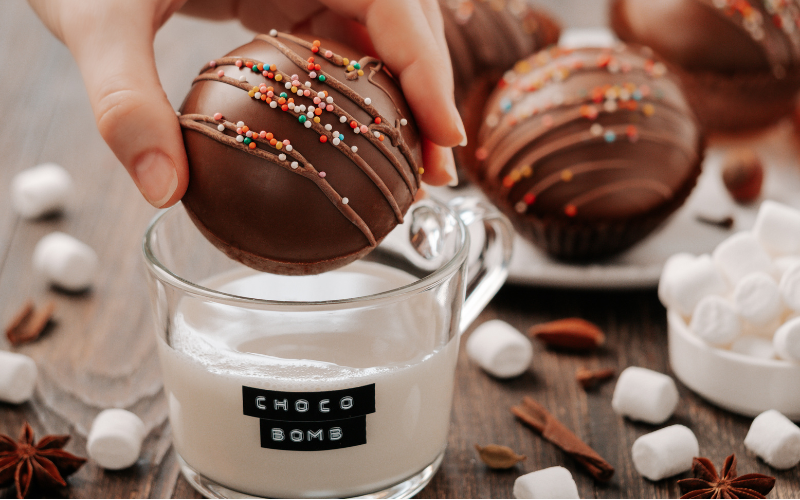 Hot chocolate bomb being added to a a cup of hot milk