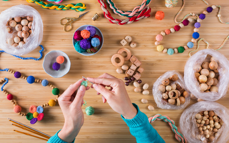 Birds-eye view of a person seated at a table with beads and string